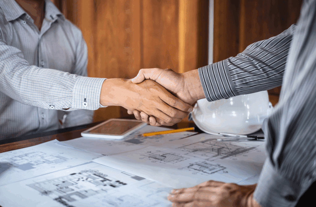 Architects shaking hands over building plans.